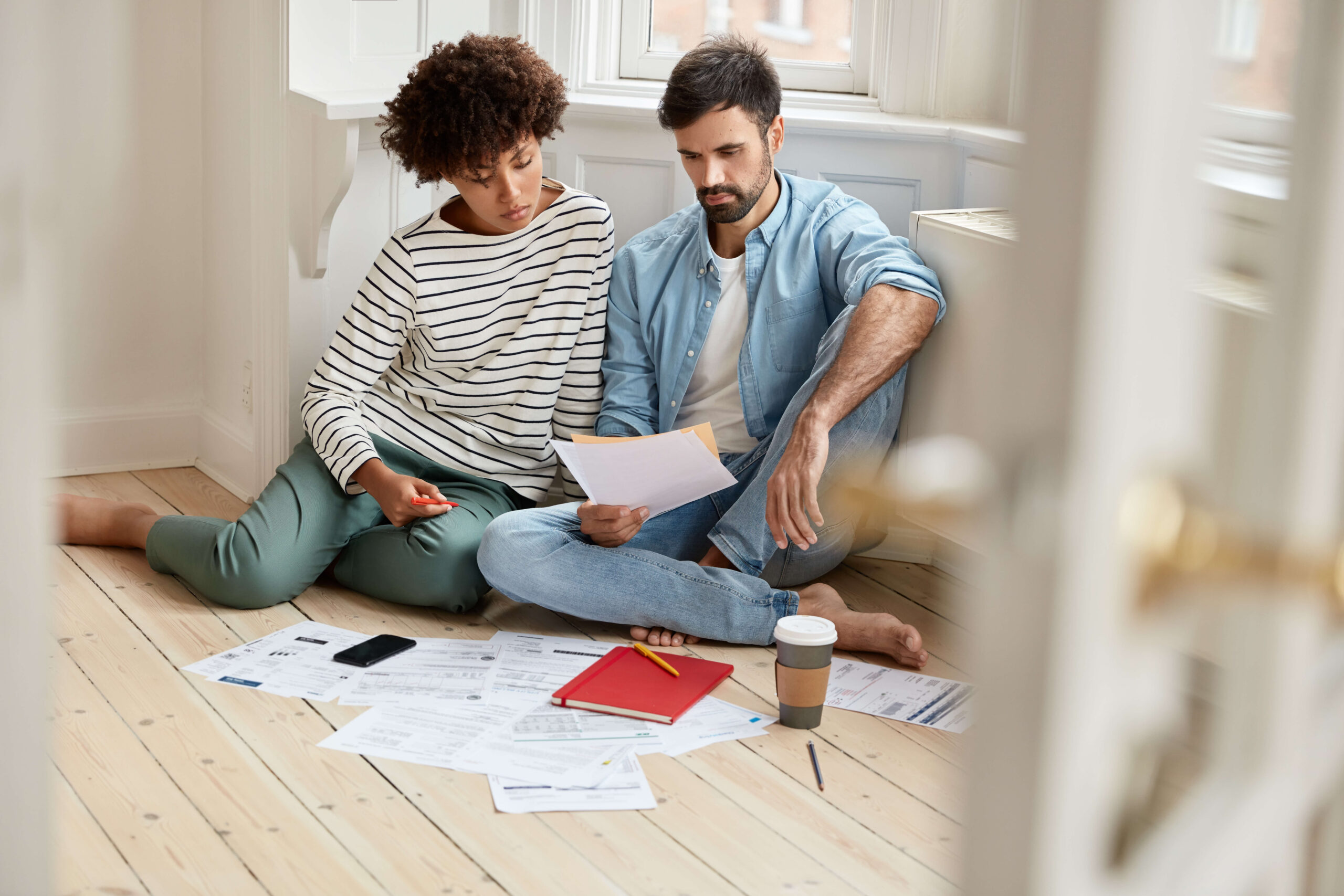 photo-mixed-race-coworkers-study-financial-bills-wear-comfortable-clothes-pose-floor-discuss-future-work-collaboration-surrounded-with-documents-coffee-cellular-working-concept-2