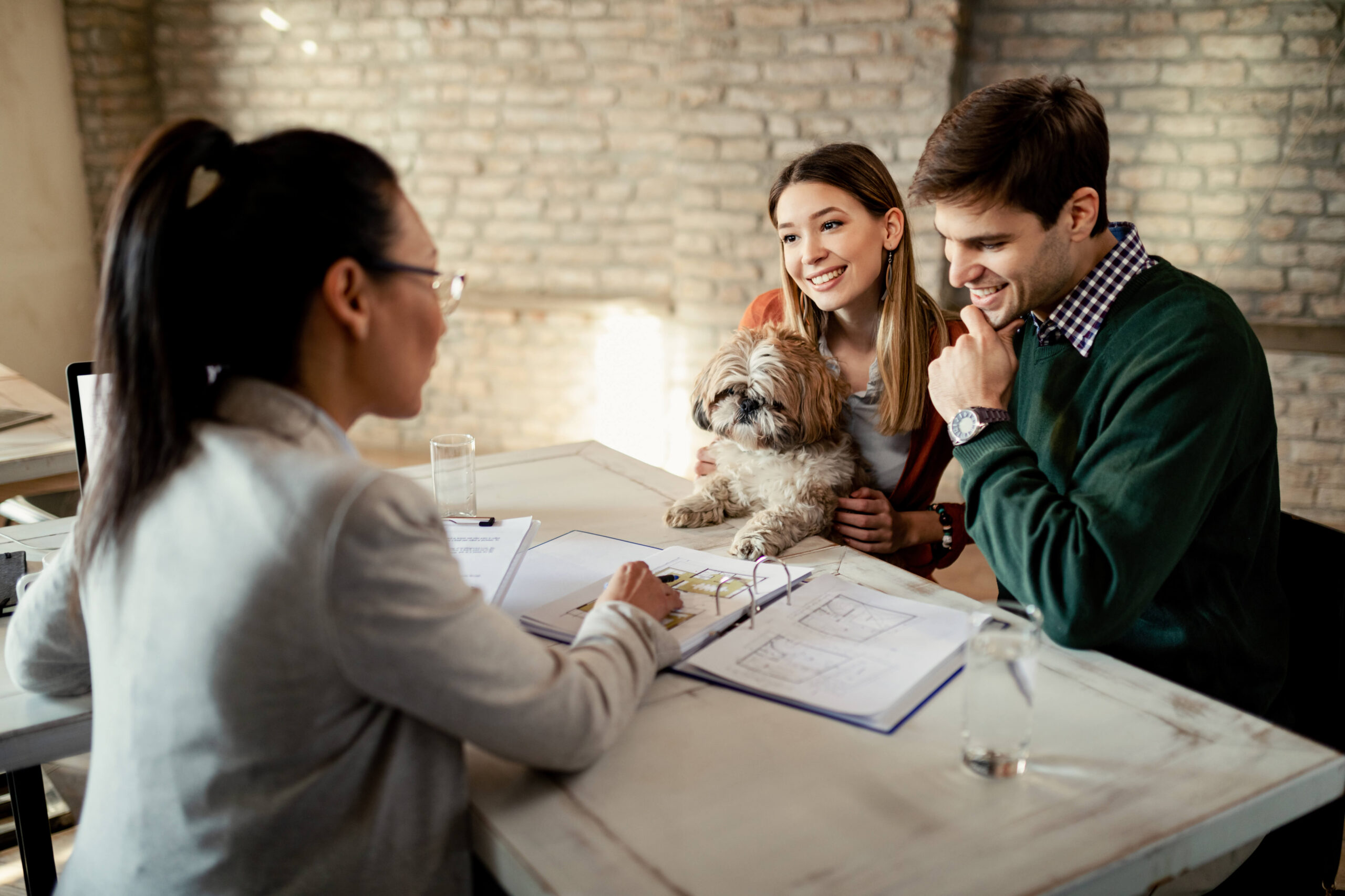 young-happy-couple-analyzing-plans-with-their-real-estate-agent-while-having-meeting-office-2
